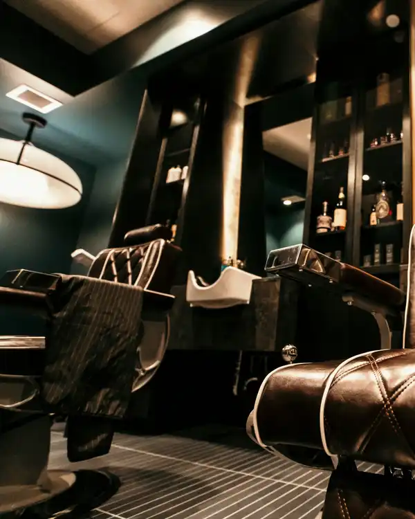 L'interno della barbieria in penombra, con la poltrona di pelle e gli specchi