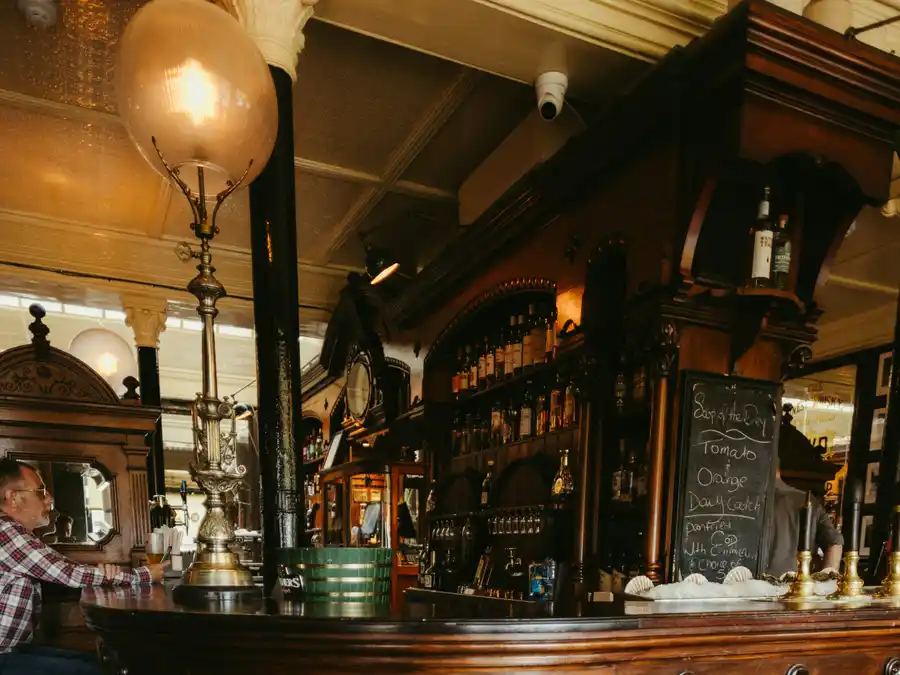 Il bancone di legno del pub, con gli sgabelli in pelle verde